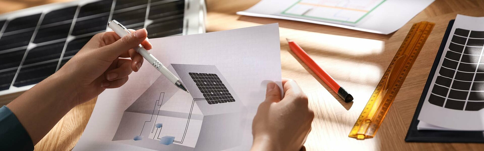 Planungsunterlagen für eine Photovoltaikanlage auf einem Wohnhaus ausgebreitet auf einem Tisch