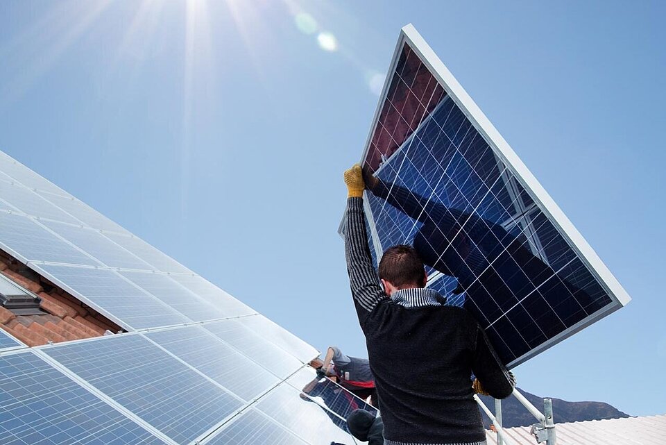 Montage von Photovoltaikmodulen auf einem Schrägdach durch zwei Solarinstallateure