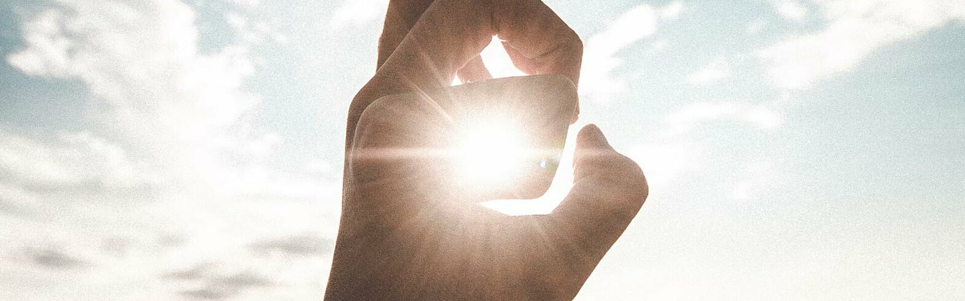 Hand die die Sonne am Himmel umrahmt als Symboldbild für FAQ zu Photovoltaik (Photo by Daoudi Aissa on Unsplash, https://unsplash.com/photos/absT1BNRDAI)