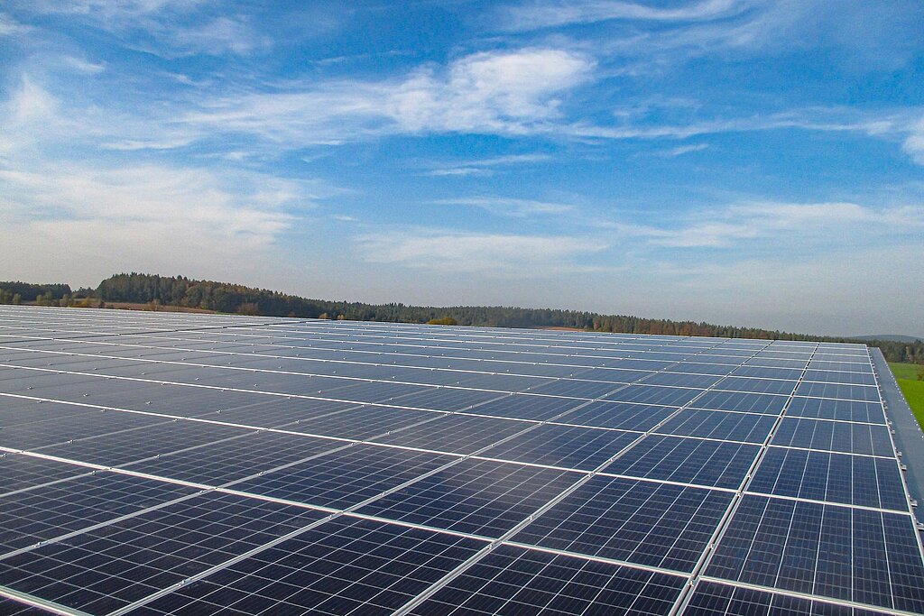 Weitläufige Dachfläche, bedeckt mit Photovoltaikmodulen vor blauem Himmel